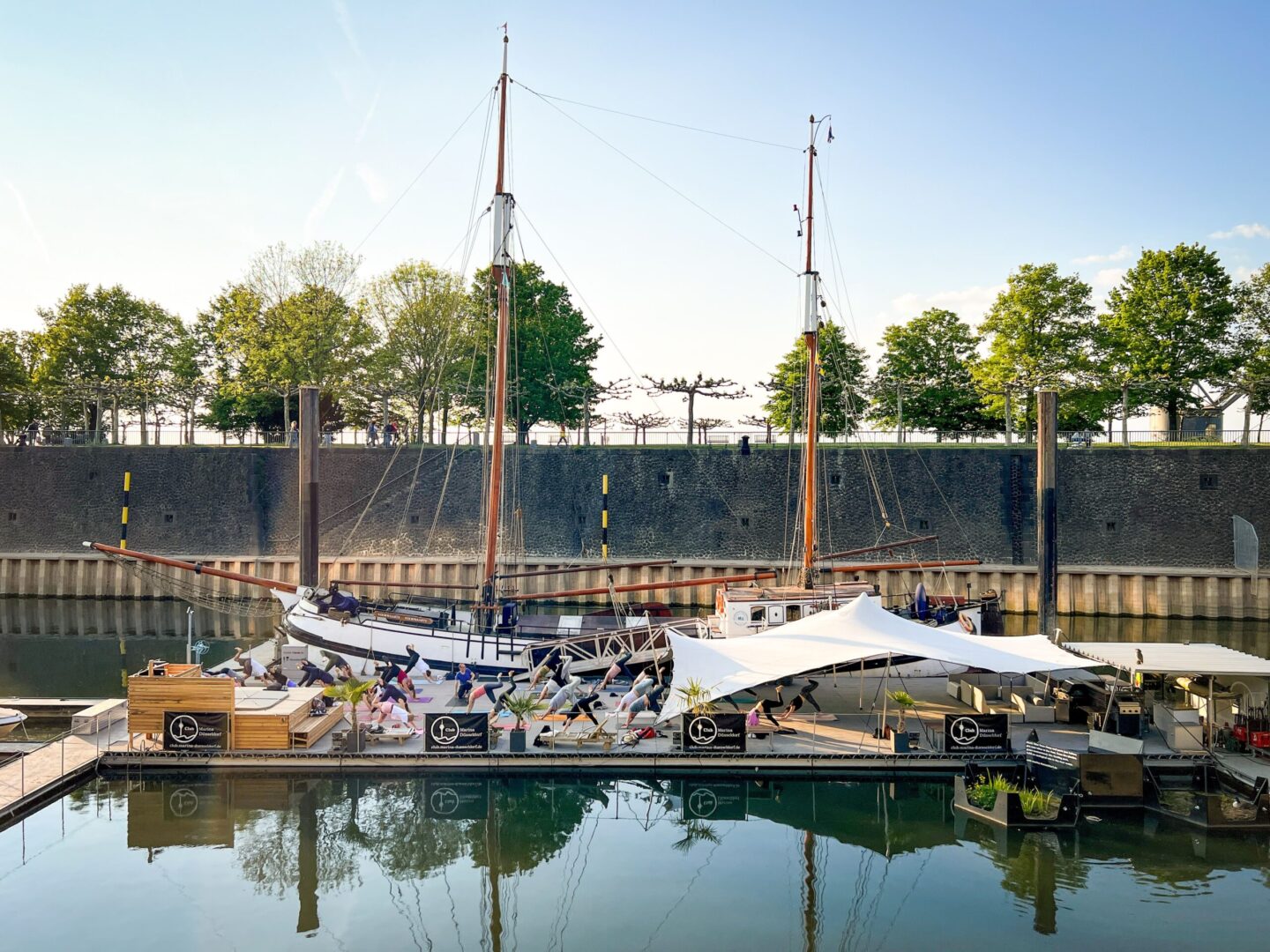 Schwimmendes Holzplateau im Hafen, auf dem Yoga gemacht wird.