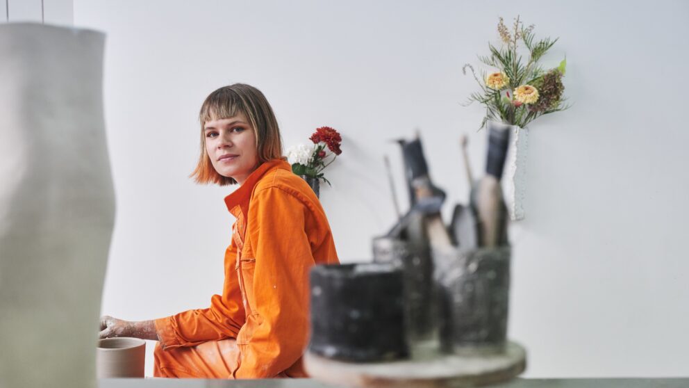 Maxi Hoffmann im orangenen Overall in ihren Kunsthandwerk Studio