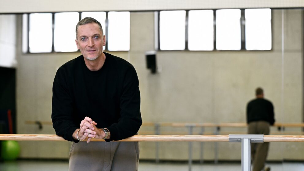 Ballet director Raphaël Coumes-Marquet stands in the rehearsal room in front of a room-sized mirror and leans against the ballet barre.