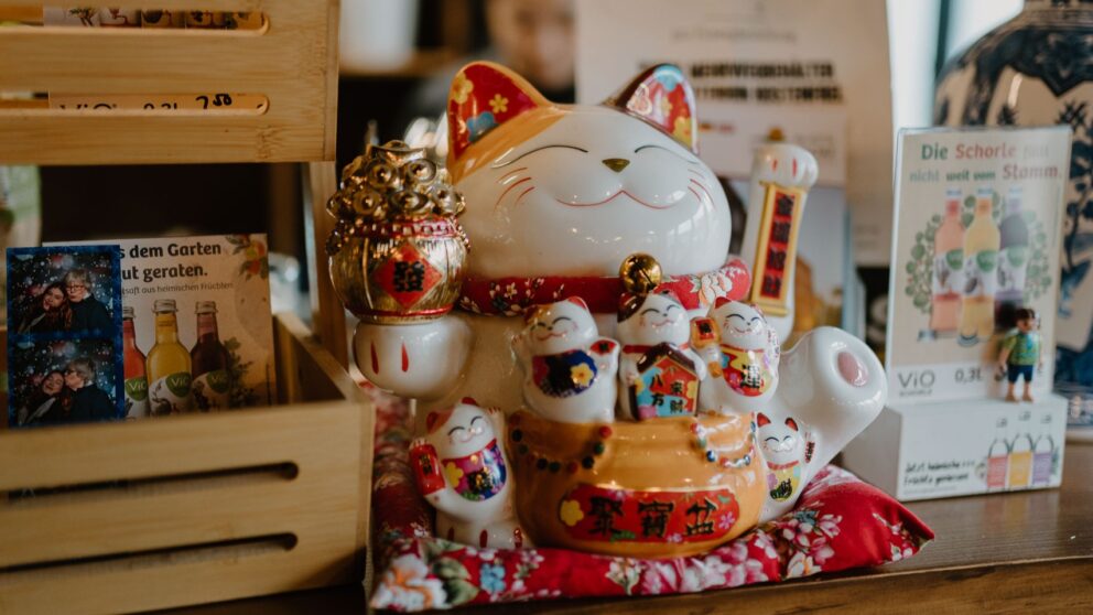Man sieht eine bunte asiatische Winkekatze auf einem Restaurant-Tresen.