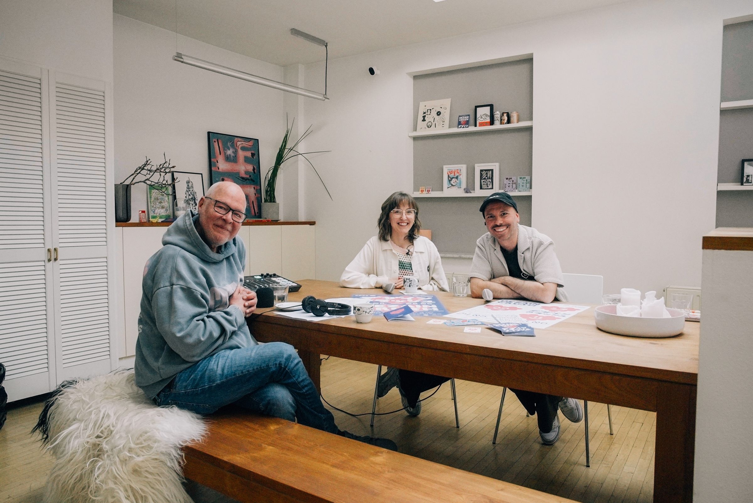Man sieht Mike Litt, links vorne, den Podcast-Host und gegenüber Lilly (links) und Alex an einem Tisch sitzend.